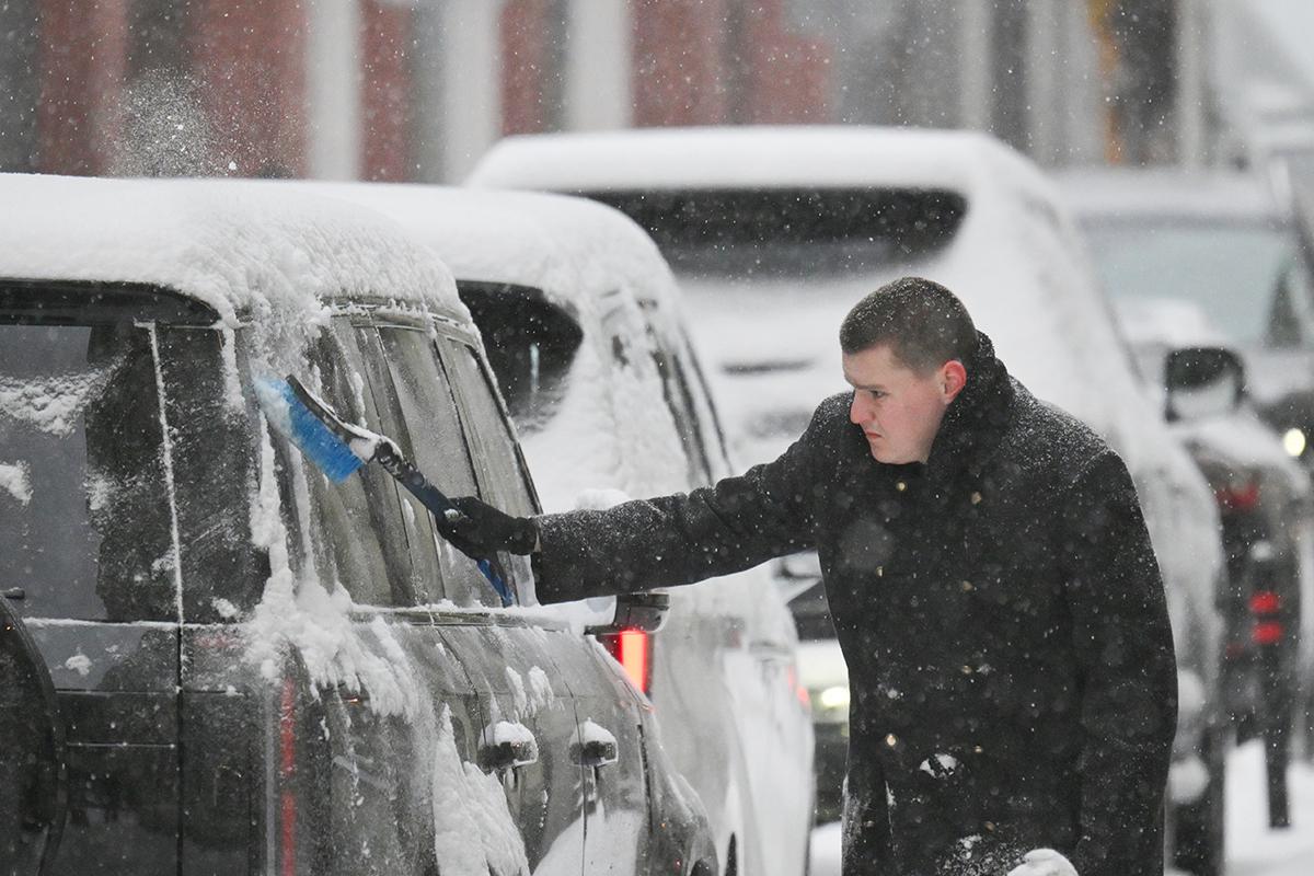 Мужчина расчищает машину от снега во время снегопада в Москве, 27 января 2026 года