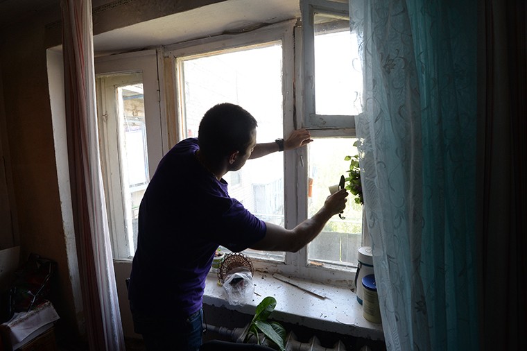 Житель города Марьинка (Донецкая область) заклеивает оконные стекла, чтобы осколки не разлетались при артобстреле. 