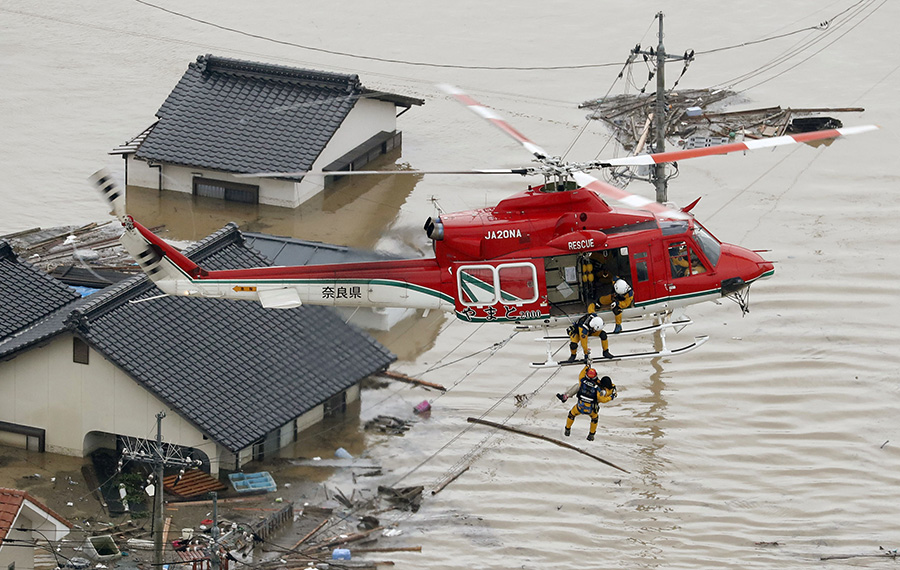 Жители затопленных территорий спасаются от наводнения на крышах своих домов. Для их эвакуации спасатели используют вертолеты