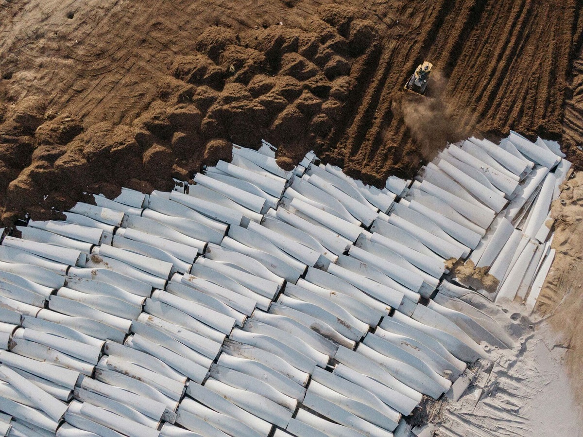 Сотни лопастей от ветрогенераторов засыпают землей на полигоне.