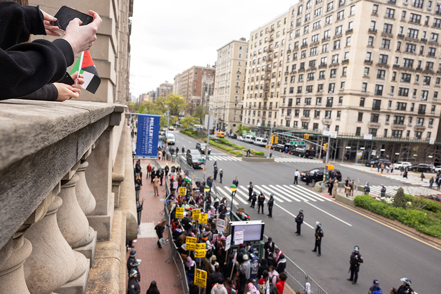 Люди наблюдают за участниками пропалестинской протестной акции снаружи Колумбийского университета, Нью-Йорк, 19 апреля 2024 года