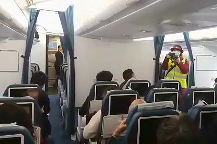 Сотрудник санитарно-карантинного пункта обследует пассажиров на борту самолета, прибывшего в московский аэропорт Внуково