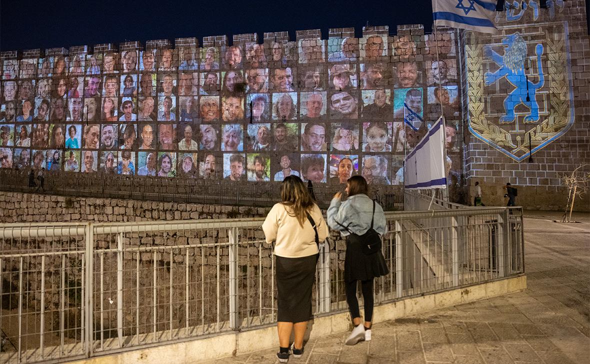 Люди стоят напротив проекции&nbsp;фотографий заложников на стены Старого города возле Яффских ворот, Иерусалим