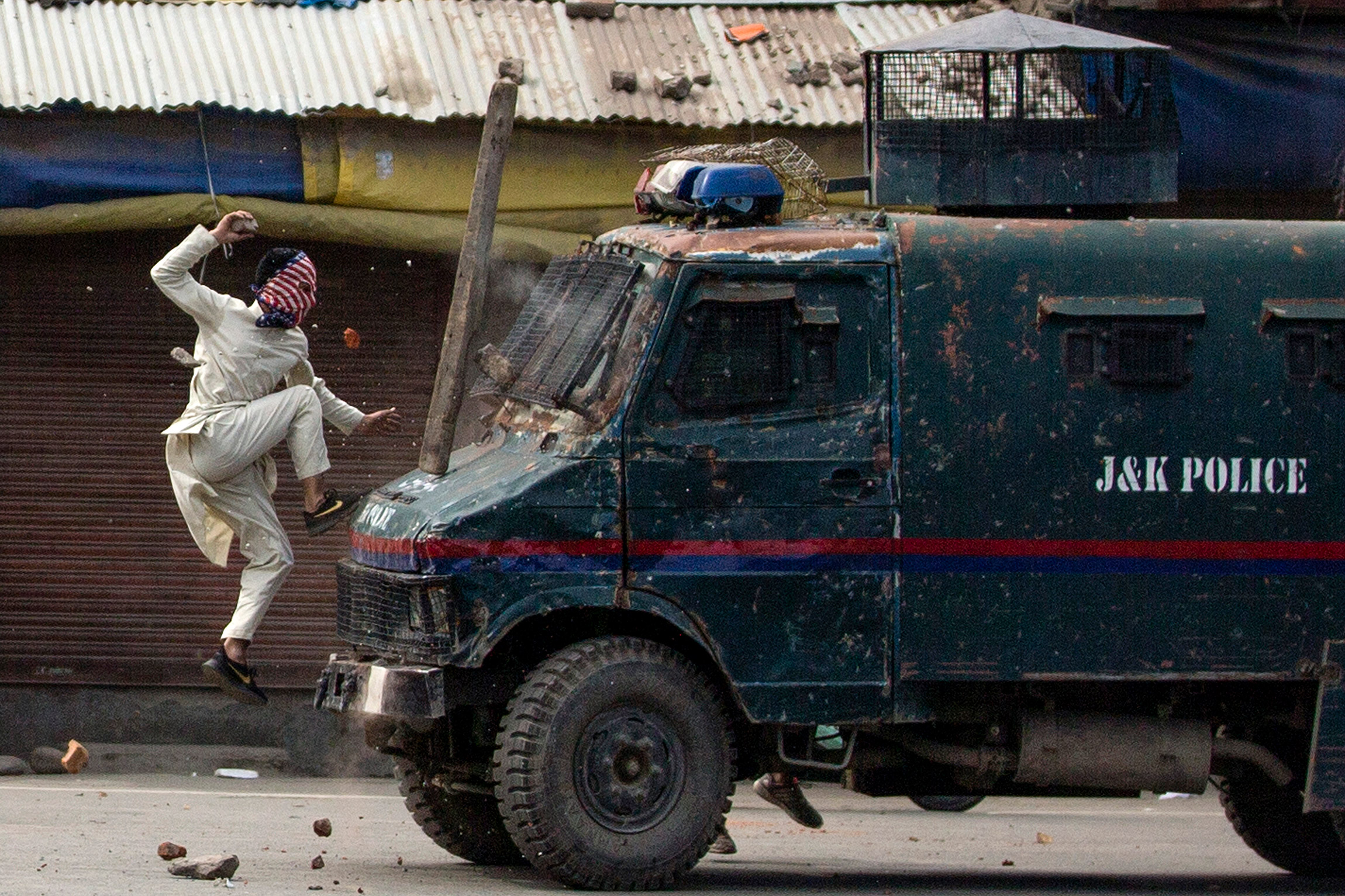 31 мая, Сринагар, столица автономного штата&nbsp;Джамму и Кашмир на севере Индии. Кашмирский протестующий в маске прыгает на бронетранспортер индийской полиции
