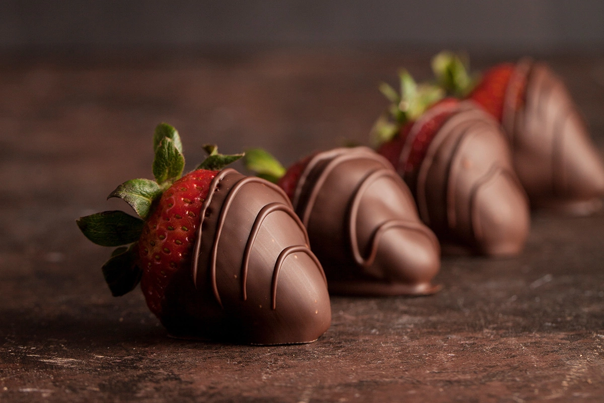 Окунайте клубнику в шоколад и выкладывайте ее на пергамент, чтобы шоколад застыл