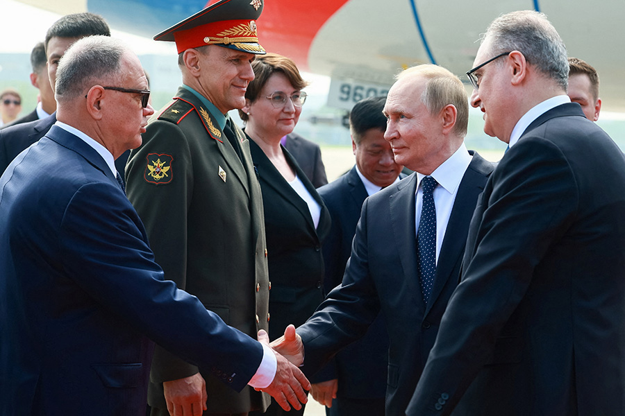 Путин пожимает руки официальным лицам во время церемонии встречи в аэропорту по прибытии на саммит ШОС.