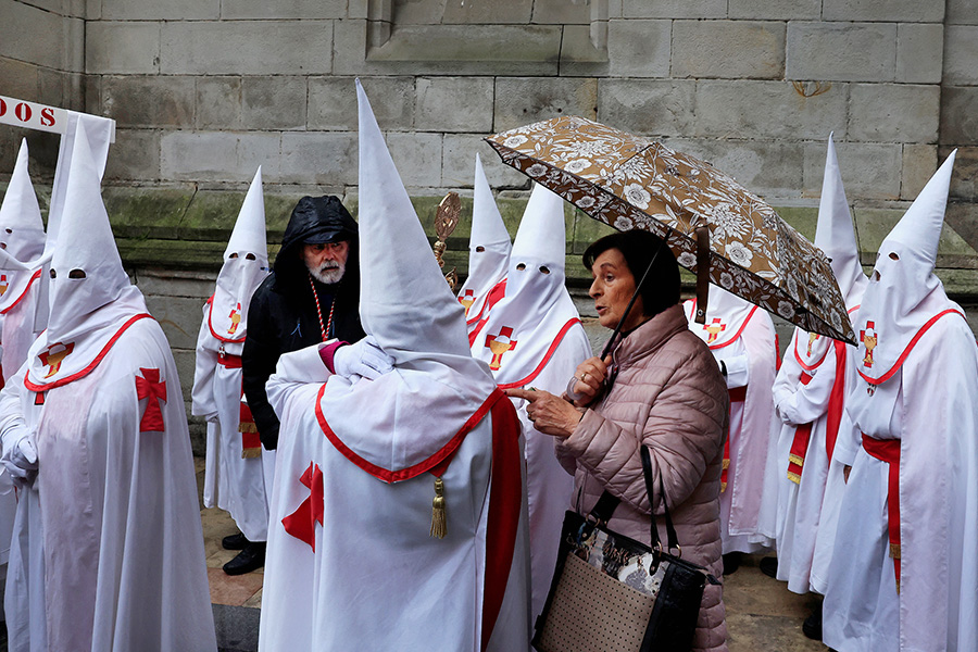 Женщина и кающиеся во время пасхальной процессии в испанском Бильбао.