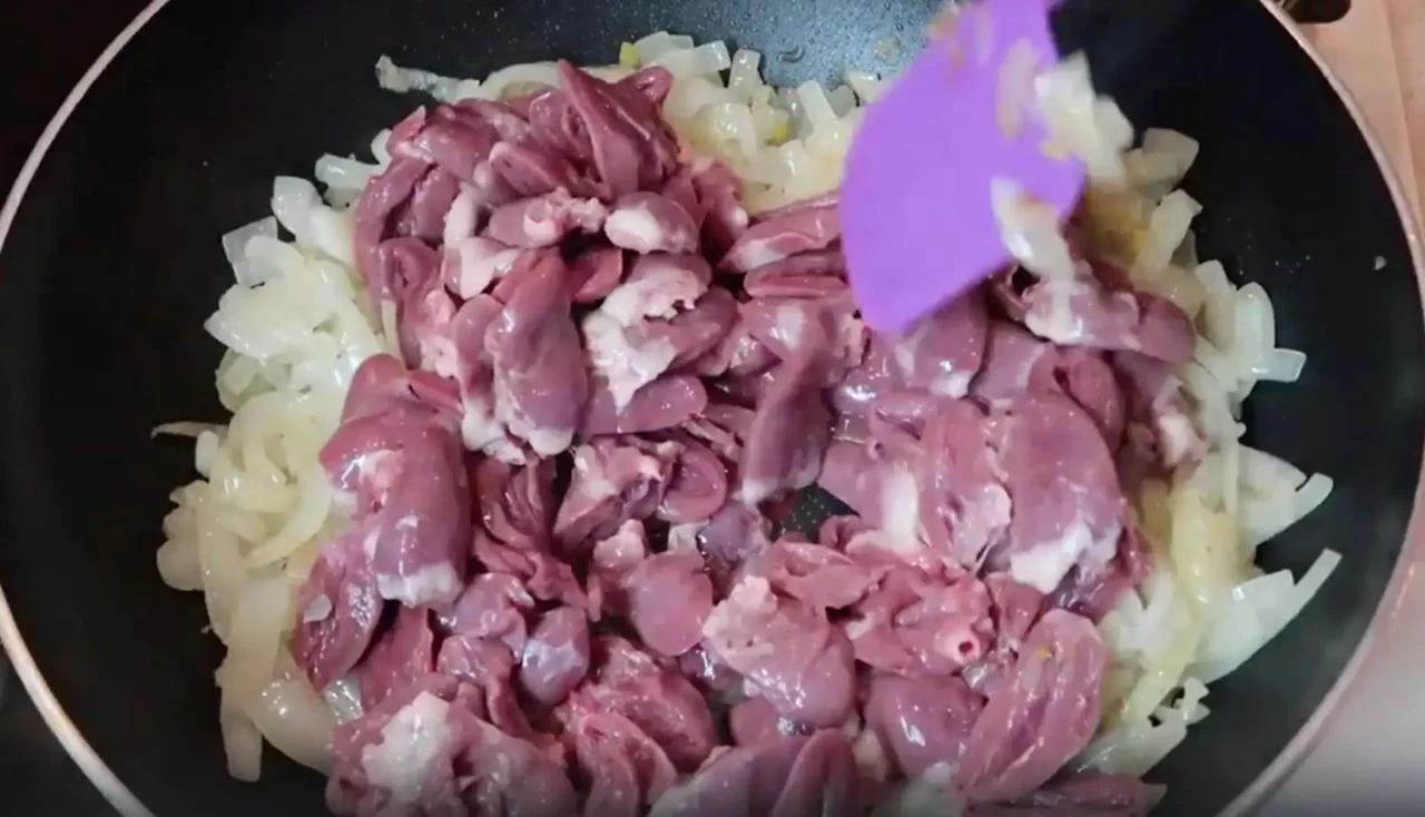 Добавьте куриные сердечки в обжаренный лук