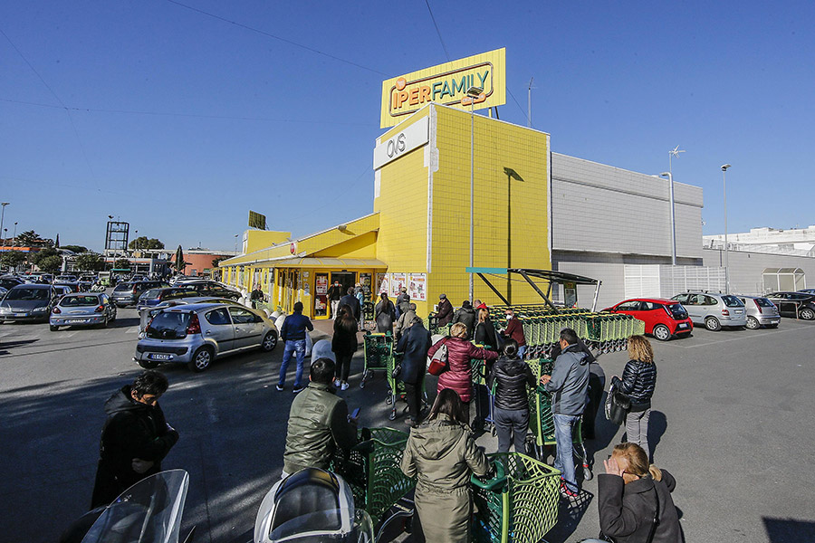 Люди стоят в очереди снаружи супермаркета в Риме, чтобы соблюсти необходимую дистанцию друг от друга
