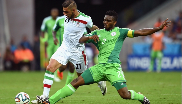 Нигериец Йозеф Йобо в борьбе за мяч с иранцем Ашканом Дежага во время матча в Группе F Иран - Нигерия. 