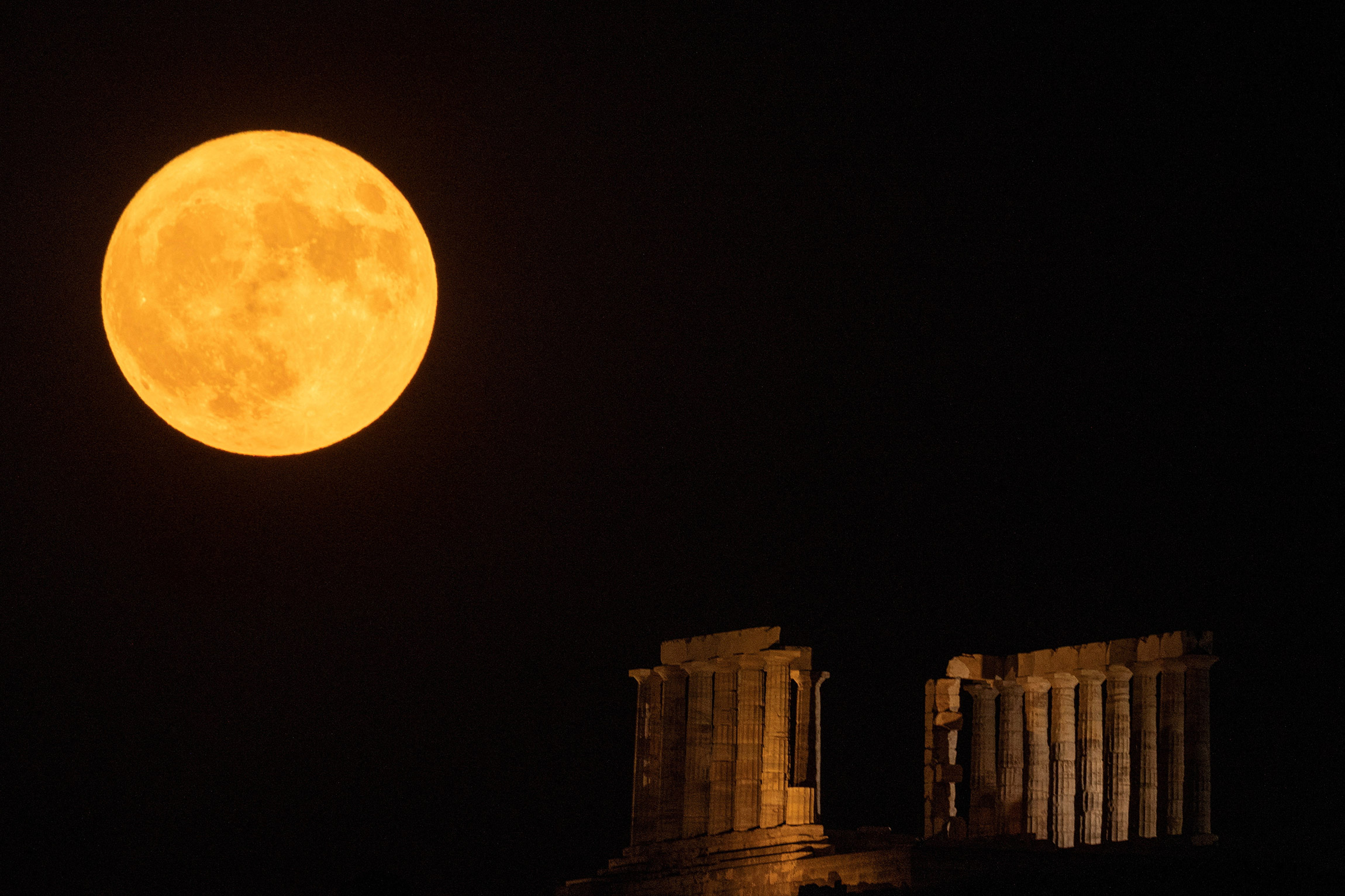 Полная луна за храмом Посейдона на мысе Сунион недалеко от Афин, Греция