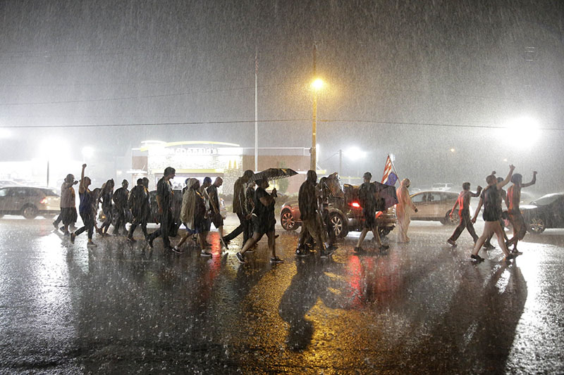 Митингующие идут по улицам Фергюсона под проливным дождем. Гроза и ливень на время ослабили уличные беспорядки и рассеяли толпу протестующих