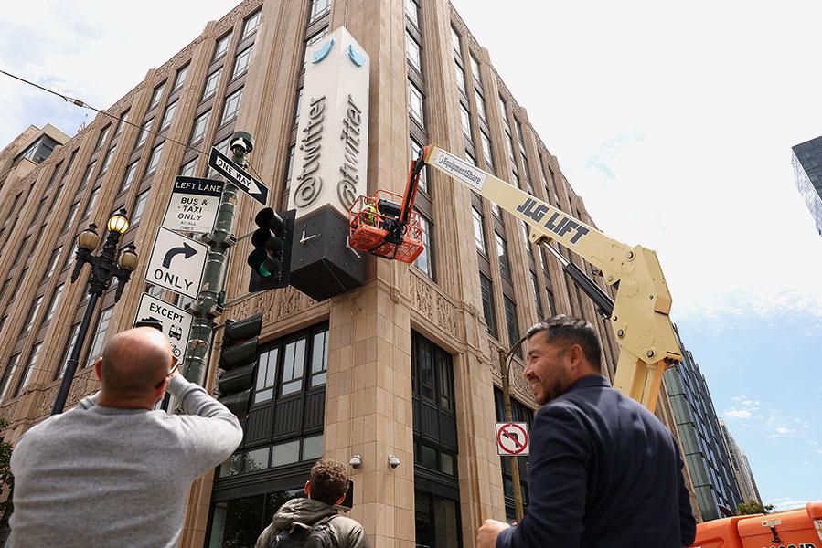 Рабочий снимает буквы с вывески Twitter, которая размещена на фасаде штаб-квартиры компании, июль 2023 года