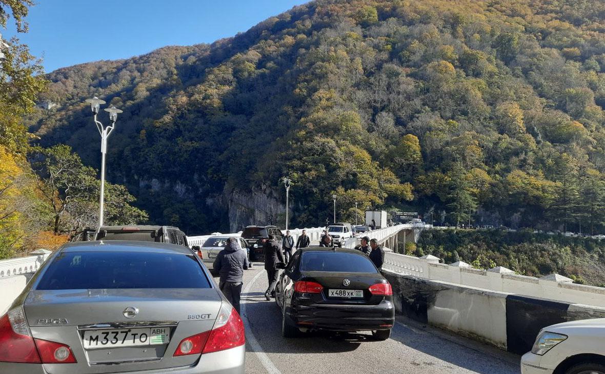 Люди и автомобили на заблокированной трассе у моста через реку Гумиста