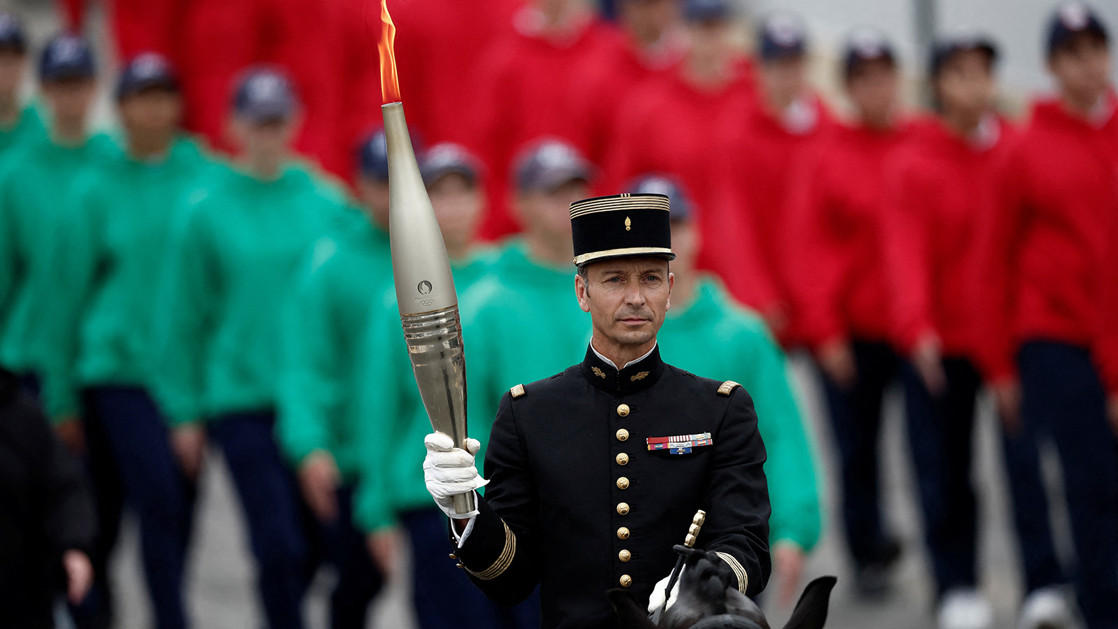 <p>Полковник Тибо Валлетт, главный наездник Le Cadre Noir и золотой медалист в командном зачете на Олимпийских играх в Рио 2016 года, держит олимпийский огонь во время парада, 14 июля 2024 года</p>