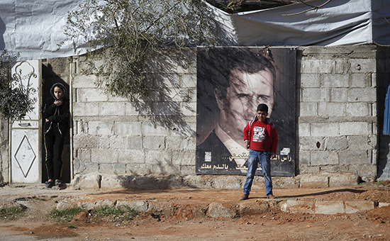 Жители окрестностей Дамаска, контролируемых правительственными войсками. На плакате президент Сирии Башар Асад