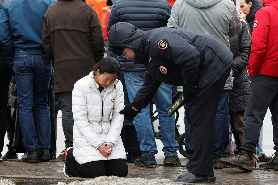 Полицейский успокаивает женщину, которая пришла к мемориалу у &laquo;Крокус Сити Холла&raquo;