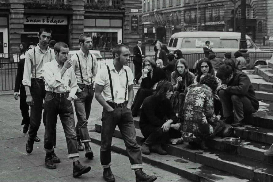 Группа скинхедов проходит мимо группы хиппи на площади Пикадилли в Лондоне, 1969 год