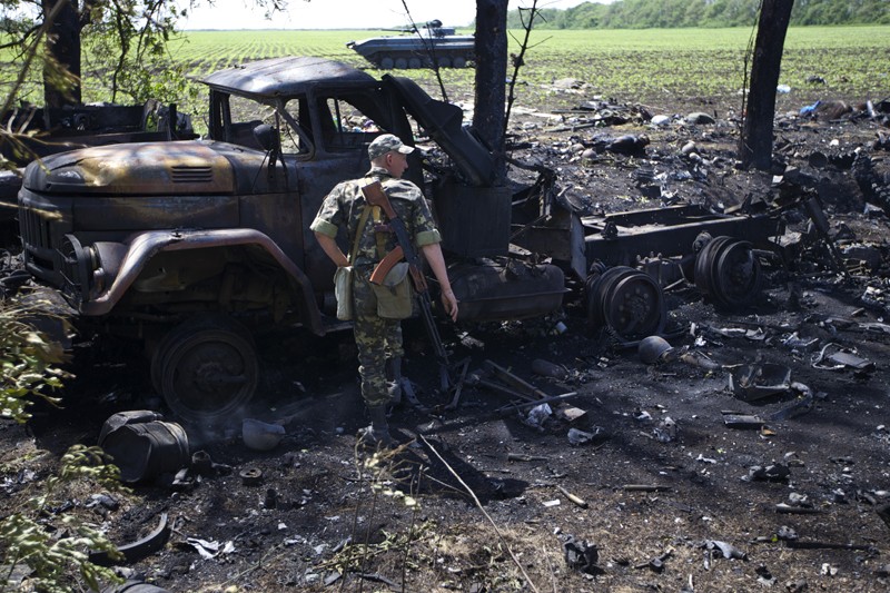 Украинский солдат стоит возле разрушенного в перестрелке грузовика около села Благодатное. 