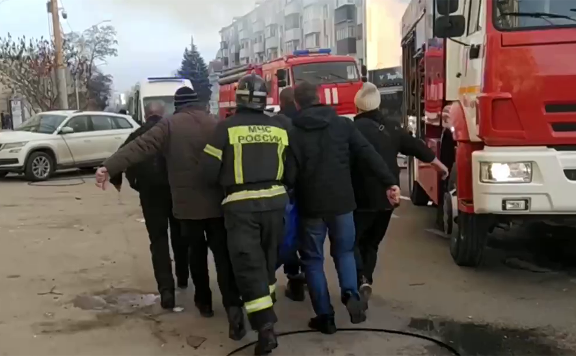 Люди уносят человека с места обстрела в Белгороде