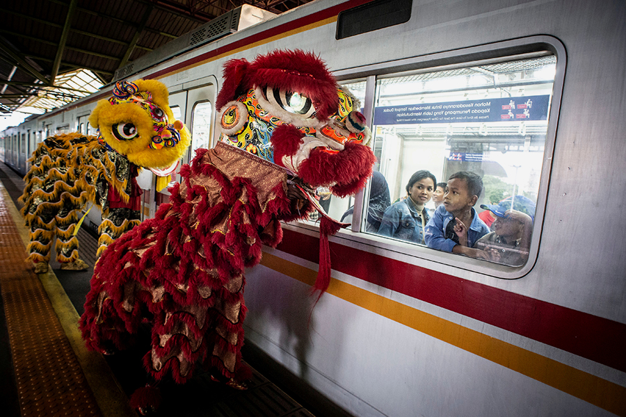 Пассажиры смотрят из окна поезда, как лев танцует на платформе станции во время празднования китайского лунного Нового года в Джакарте (Индонезия)