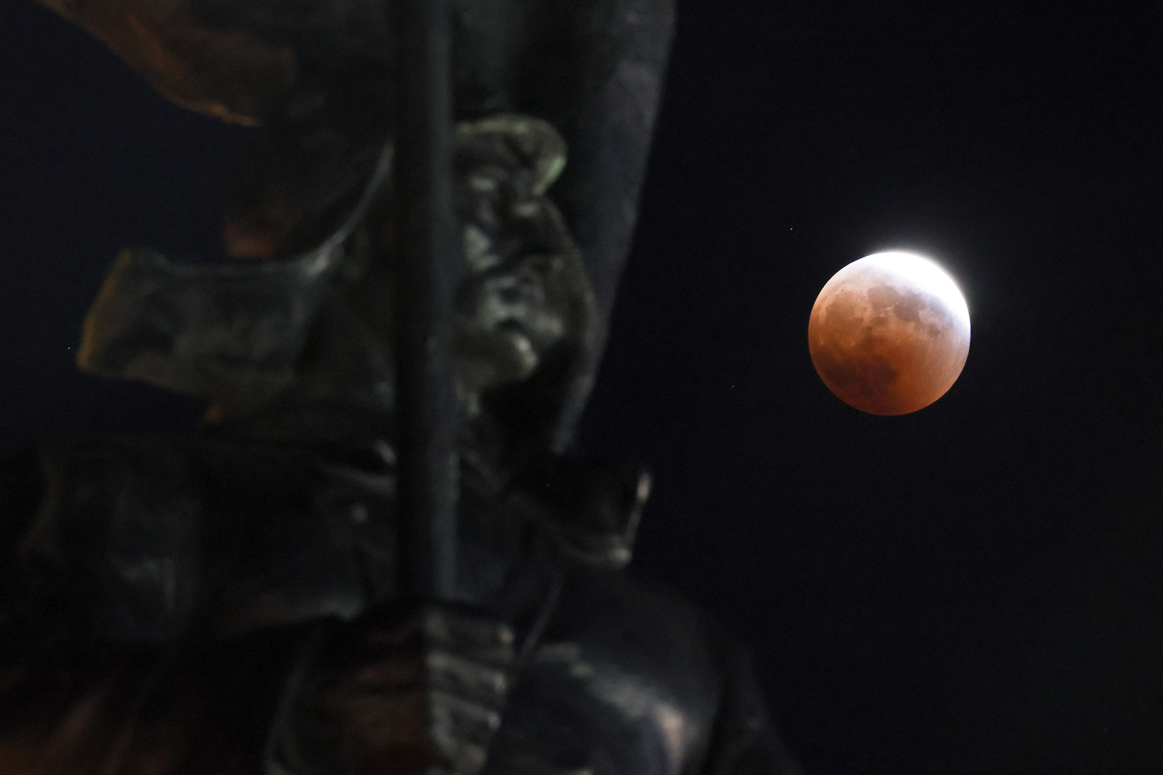 Вид на лунное затмение через памятник Борцам за власть Советов, Дальний Восток