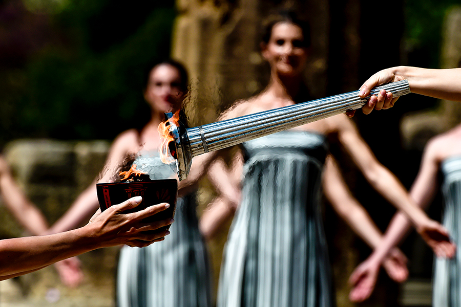 Кадр с официальной церемонии зажжения олимпийского огня, на которой верховная жрица зажигает факел от огня, полученного во время генеральной репетиции