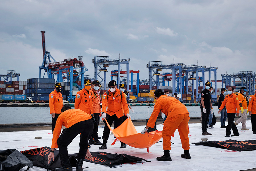 Индонезийские спасатели несут мешки с останками погибших при крушении и обломками Boeing