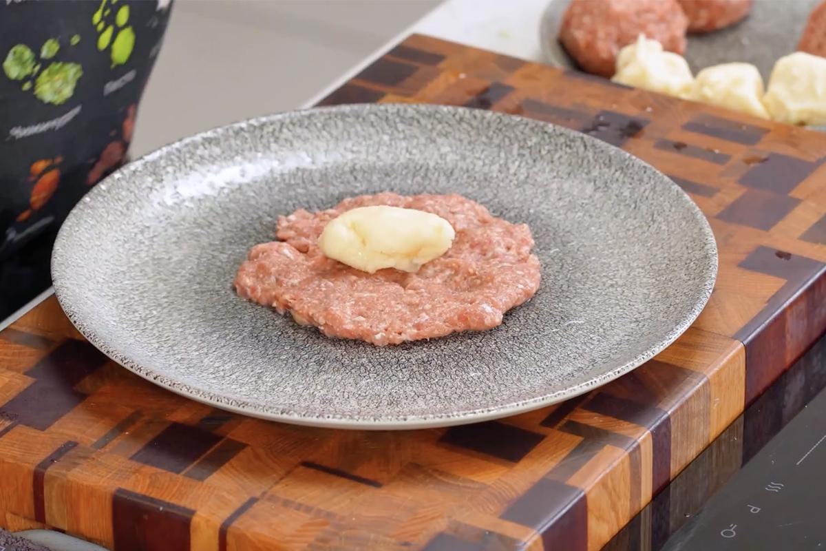 Выложите в центр мясной лепешки начинку