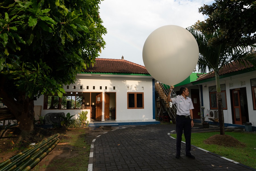 Наблюдатель на метеорологической станции на Бали выпускает большой белый шар-радиозонд