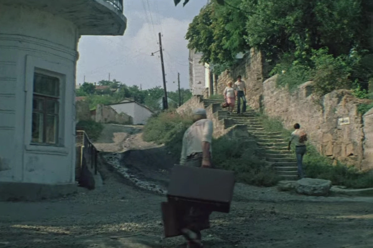 Степан следит за Костиком на улицах вымышленного кинематографистами города Южногорска, кадр из фильма «Спортлото-82»