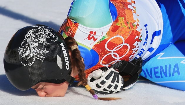 Tina Maze из команды Словении, занявшая первое место, целует землю после своего победного спуска в горнолыжном центре «Роза Хутор»