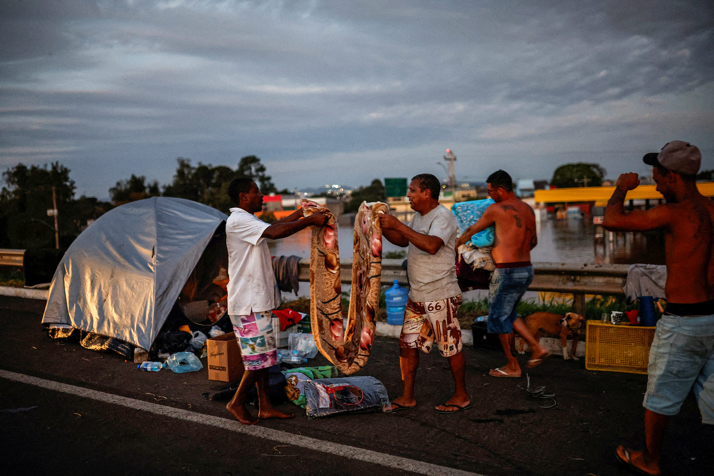 Люди организовали лагерь на мосту возле затопленной улицы в муниципалитете Элдораду-ду-Сул.
