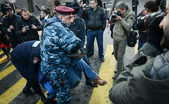 Сотрудники службы безопасности несут мужчину во время акции протеста у посольства России в Ереване