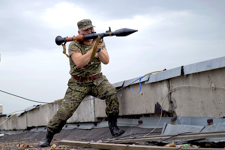 Ополченец готовится выстрелить из гранатомета по части украинских пограничников в Луганске.
