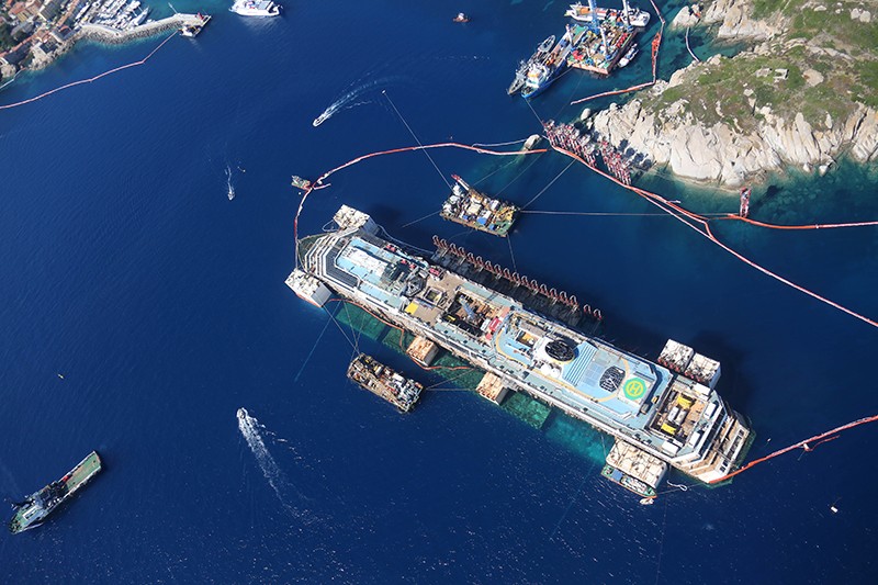 В море лайнер сопровождают две баржи, 10 кораблей и два вертолета. Еще 12 специалистов следят за состоянием Costa Concordia, находясь на его борту. 