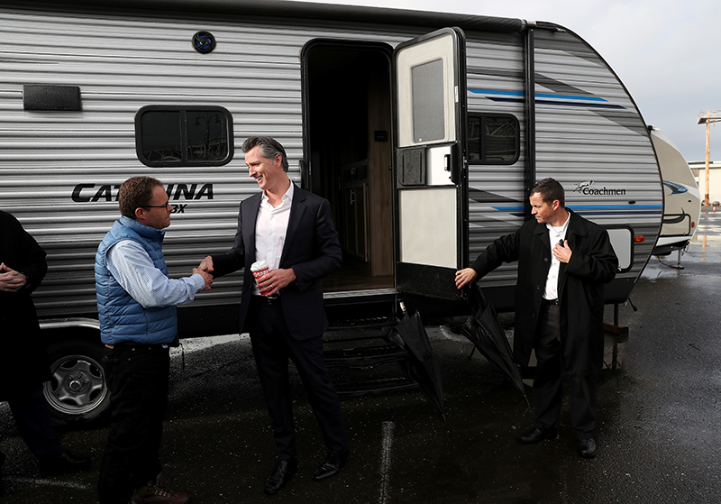 Гэвин Ньюсон приветствует людей у трейлеров FEMA после конференции, посвященной бездомным, Окленд, Калифорния


