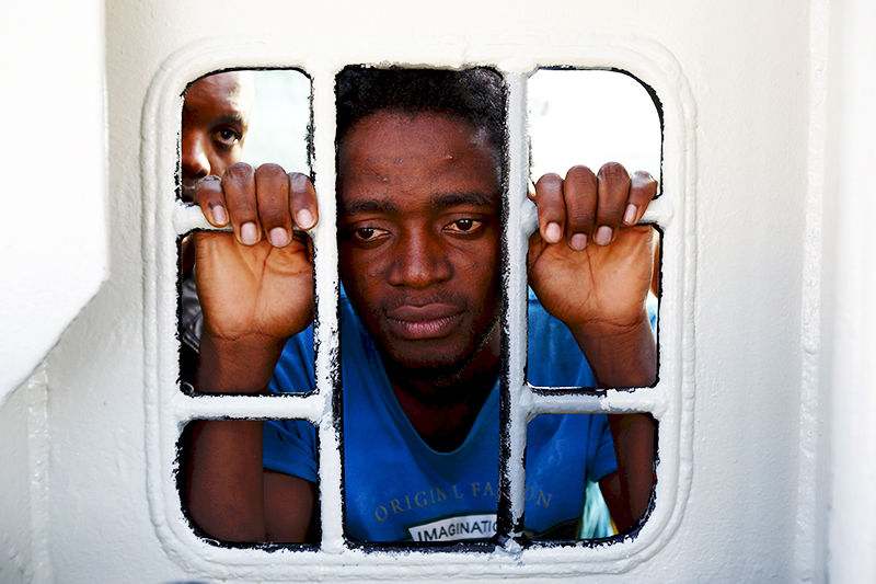 Беженец из Северной Африки выглядывает из окна спасательного корабля организации &laquo;Врачи без границ&raquo;, прибывшего в итальянский город Трапани




