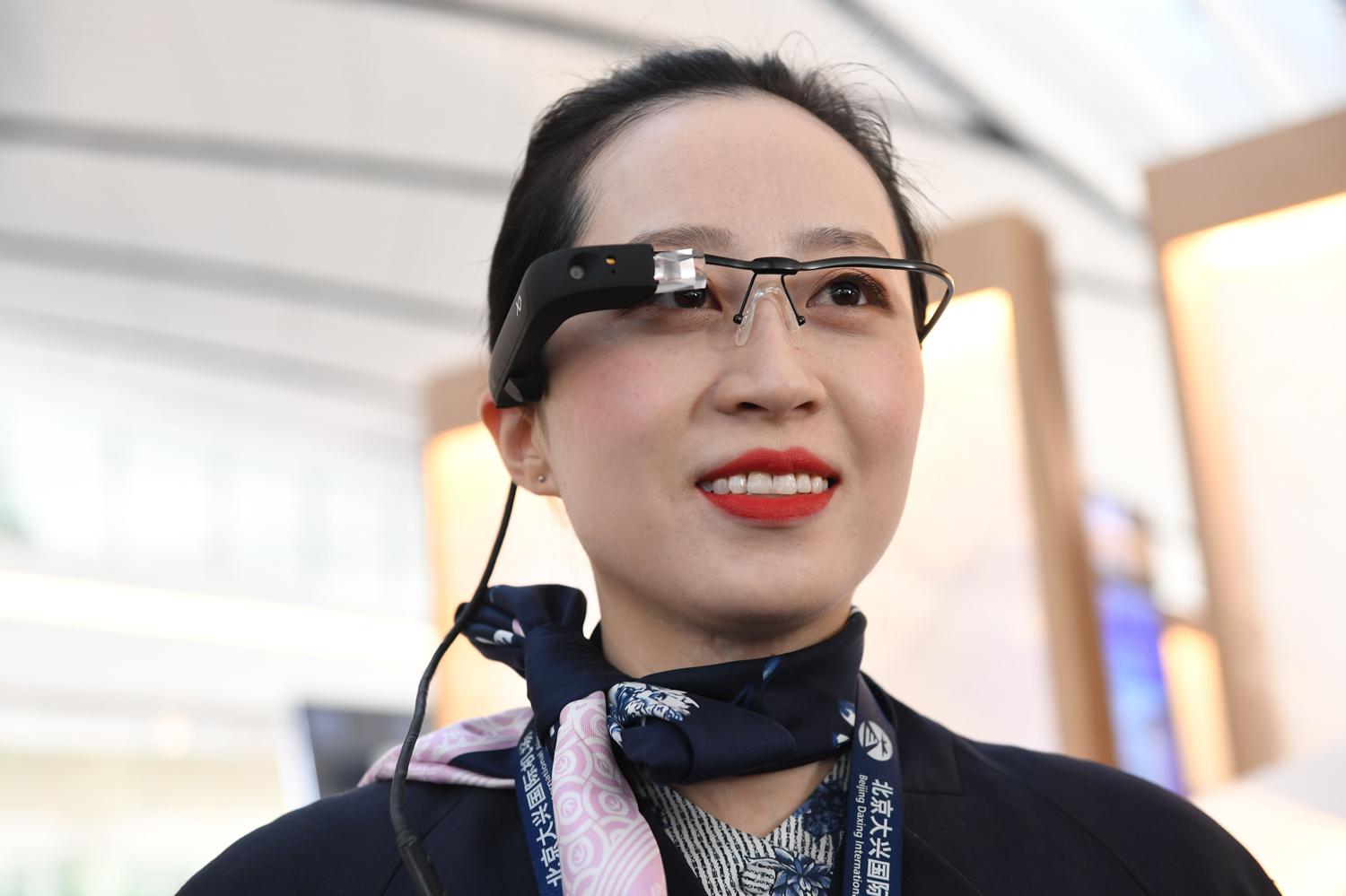 Сотрудница авиакомпании China Eastern Airlines в очках дополненной реальности с функцией распознавания лиц в пекинском международном аэропорту Дасин