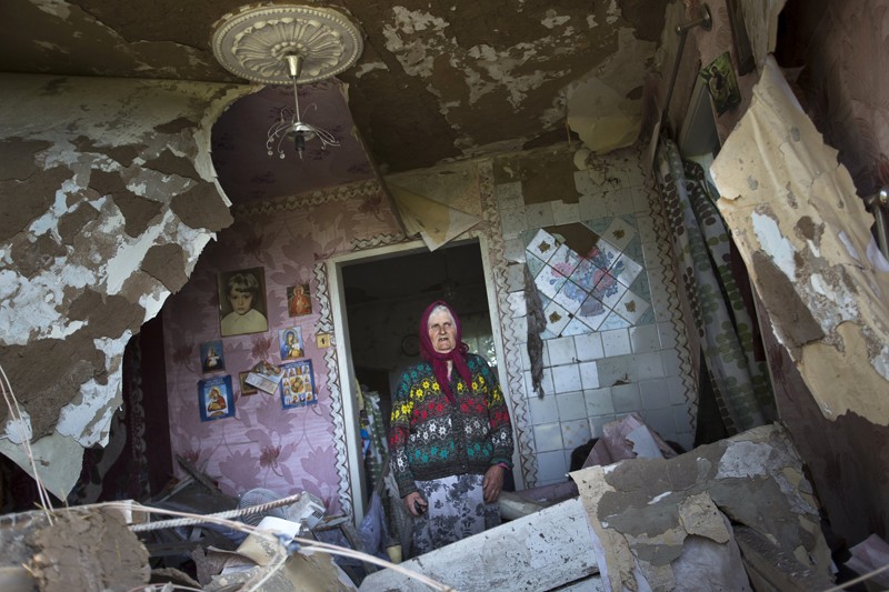 80-летняя Зинаида Пацкан стоит в своем разрушенном от обстрелов доме в деревне Семеновка. 