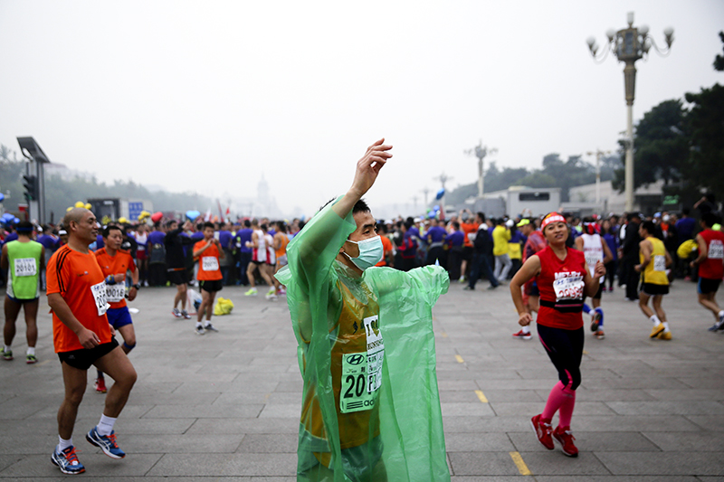 Спортсмен в маске на старте международного марафона в Пекине.
