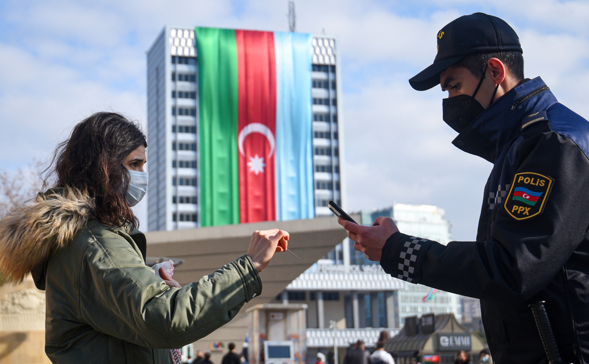 Сотрудник полиции проверяет пропуск у девушки на одной из улиц в Баку