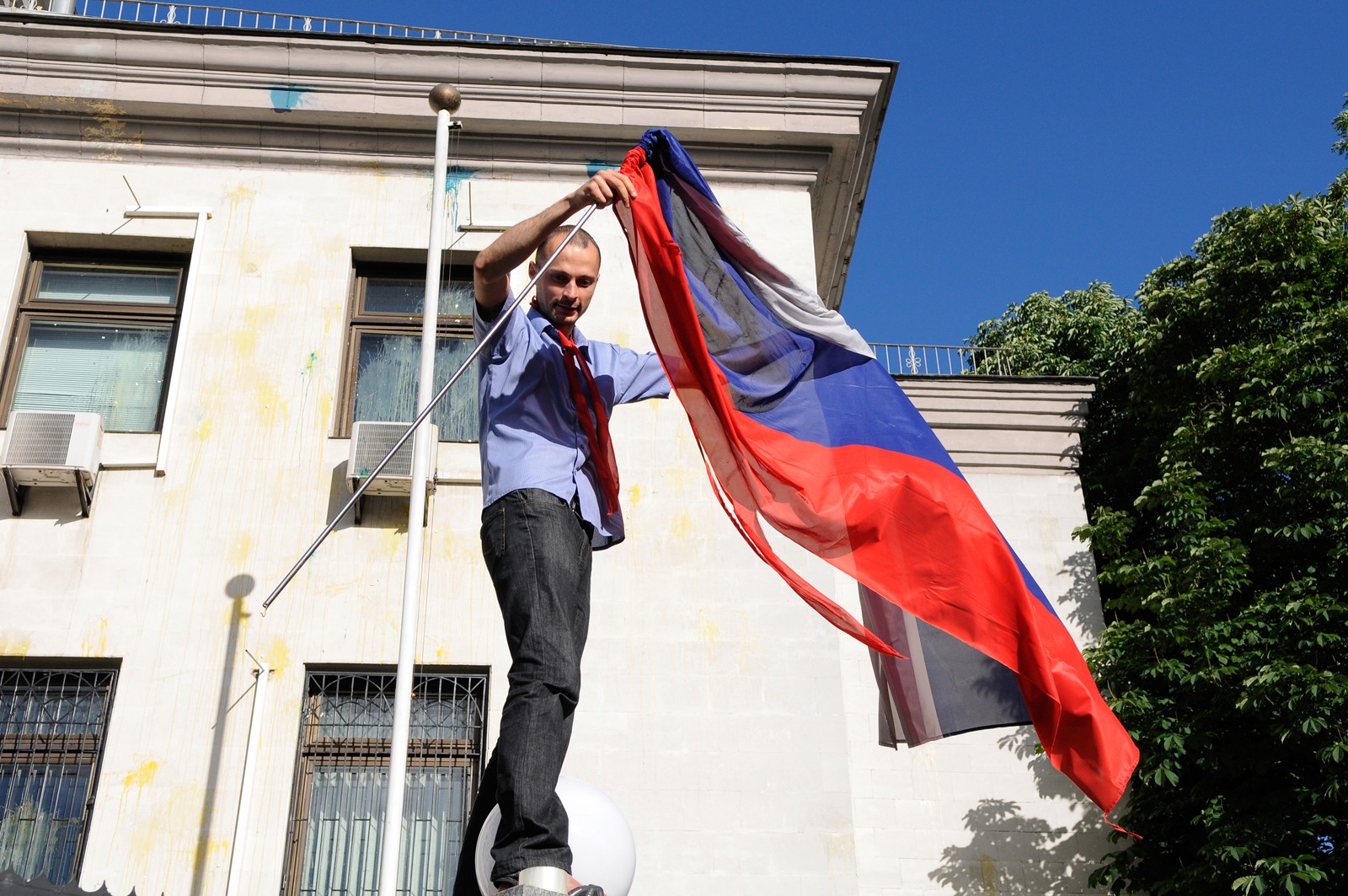 Один из участников беспорядков устроенных представителями националистицеских организаций у посольства России в Киеве срывает флаг Российской Федерации.