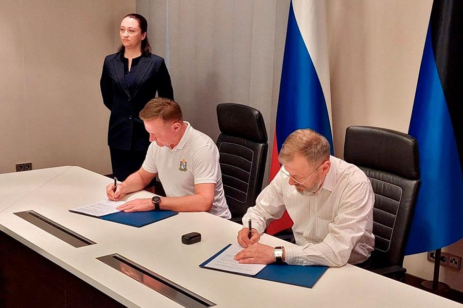Роман Старовойт (слева) подписывает соглашение о сотрудничестве с главой администрации Первомайского района ДНР Борисом Трима, июнь 2022 года