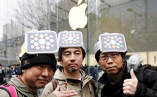 Мужчина в картонной шляпе, изображающей Apple Watch, позирует перед магазином компании в Токио