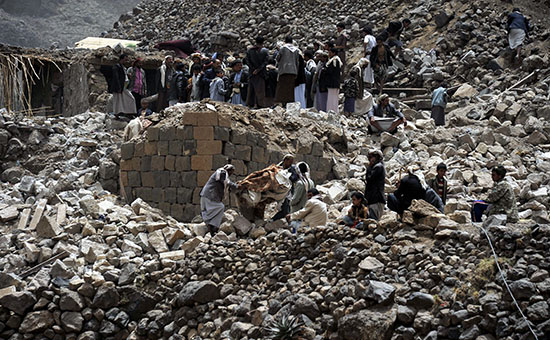 Жители Йемена после бомбардировок города Сана на обломках своих домов