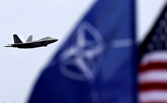 Истребитель ВВС&nbsp;США F-22 Raptor, флаги НАТО и США на авиабазе Шяуляй в Литве


