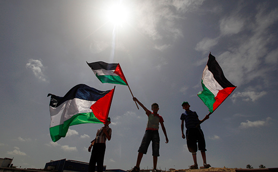 Палестинские мальчики размахивают национальными флагами
