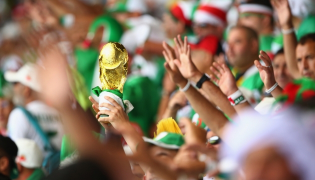 Болельщики поднимают вверх копию Кубка Чемпионата мира по футболу на стадионе "Минейран"  во время матча в Группе H  Бельгиея - Алжир. 17 июня, Белу-Оризонти, Бразилия. 