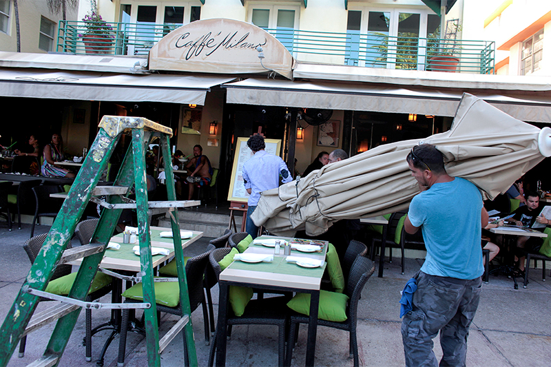 Работники ресторана в Майами (Флорида, США) убирают с улицы столы и зонтики в ожидании урагана &laquo;Мэттью&raquo;
